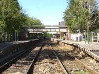 A view west through Sherborne Station from Gas House Hill level crossing on 12 May 2015. The main up side building stands beyond a now rare Southern Railway style fully roofed footbridge.<br><br>[David Pesterfield 12/05/2015]