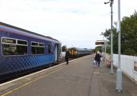 Platform scene at Girvan on 12 August 2015. The Conductor / Guard of the 09.38 Glasgow to Stranraer waits to give the right-away as the 10.10 Stranraer to Kilmarnock (change at Ayr for the 11.52 EMU to Glasgow Central) departs northward.<br><br>[Colin Miller 12/08/2015]