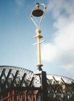 Cast iron light fitting on the footbridge between plastforms 6 and 9/10 at Stirling in January 1995. Platform columns in this pattern [see image 20007] had only recently been replaced. The fittings on the bridge survive, though they have heritage-style imitation gas lamps (made by Sugg, who made station gas lamps and are still around) and the paintwork is all black.<br>
<br><br>[David Panton 05/01/1995]