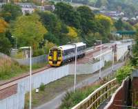 Heading north out of Galashiels on 9 October 2015, a late morning Tweedbank - Edinburgh service has just crossed the bridge over Wheatlands Road. The ramp bottom right now links the parallel walkway with Kilnknowe Place.<br><br>[John Furnevel 09/10/2015]
