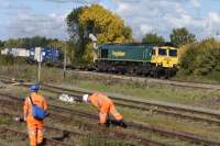 66589, on an eastbound container train, passes a Network Rail gang engaged on track maintenance in the sidings at Didcot on 081015. <br><br>[Peter Todd 08/10/2015]