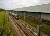 Only eight months ago [see image 50466], this Eddie Stobart warehouse was just a steel frame. Now it is in use, ready to exchange freight with the line of Cargowaggons on the siding. The 350 is heading for London via Northampton.<br><br>[Ken Strachan 23/10/2015]