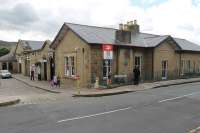 Part of Glossop station has been tastefully incorporated into a supermarket, built in matching stone, and the railway now only occupies the extreme right of the building. Everything beyond the arched door under the blue sign is now in retail use. The station is still staffed and enjoys a 30 minute frequency service to Manchester.  <br><br>[Mark Bartlett 01/09/2015]