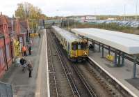 A Merseyrail service heading for Liverpool calls at Birkenhead North, where a number of original station buildings are still in use. Just beyond the bridge is Birkenhead North EMU Depot, and some of the buildings can be seen above the car park.<br><br>[Mark Bartlett 16/11/2015]