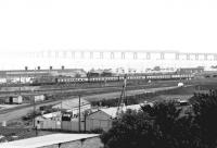 A Glasgow - Dundee train runs past the yards at Dundee West on 26 May 1980 as it nears its destination. In the background the Tay Bridge disappears into the mist.<br><br>[John Furnevel 26/05/1980]