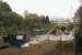 A view over the work site at the south end of Farnworth Tunnel on 31 October 2015. Since my last visit the TBM has completed it's task and much of the plant has been cleared although there are still several tasks to be completed before the track is laid. For the moment services continue to use the single line through the Down tunnel like the pair of Class 150s that are passing behind the sleeper screen.<br><br>[John McIntyre 31/10/2015]