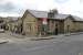 Part of Glossop station has been tastefully incorporated into a supermarket, built in matching stone, and the railway now only occupies the extreme right of the building. Everything beyond the arched door under the blue sign is now in retail use. The station is still staffed and enjoys a 30 minute frequency service to Manchester.  <br><br>[Mark Bartlett 01/09/2015]