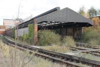 The abandoned Mersey Railway carriage depot at Birkenhead Central (BC), as seen from the station platform in November 2015. The third rails have been removed from the depot tracks but the siding alongside is still live and appeared to be used occasionally. The depot sits in a deep hollow so redevelopment of the site may not be straightforward. EMU maintenance on the Wirral side of the Mersey is now concentrated at Birkenhead North (BD).<br><br>[Mark Bartlett 16/11/2015]