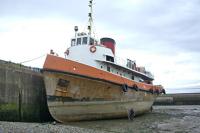 Former Clyde Shipping tug/tender 'Flying Buzzard' (perhaps the last steam tug built for use on the Clyde), built by Fergusons at Port Glasgow, 1951, ingloriously run down and sunk by her tow (a tanker) in the river off Dumbarton, 1952. Raised and repaired, she carried on working on the Clyde then at Dundee thereafter. She arrived at Maryport in Cumbria during 1983 and was part of the maritime museum there for 20 years, but when that closed she was purchased by Julie Jessop and Mike Nelder, who had visions of sailing her to Vancouver (why there I never found out!) and set about converting her for that voyage, bearing in mind her boilers had been removed so 'new' main engine and gearbox had to be fitted. Vessel photographed in the outer harbour at Maryport, 01 August, 2007, having been moved out from the wet basin to allow yours truly to visually survey the hull (which was in excellent overall condition due to all those years in almost fresh water in the Clyde and Tay estuaries). She eventually sailed from Maryport in December, 2008 and was seen, again by yours truly, in Trinidad, 15 November, 2009, the extension of the voyage to Vancouver having been temporarily put on hold. As far as is known, at the start of 2016 she was still in the Caribbean, having never gone any further (we can only surmise that Mike and Julie liked the Caribbean and decided to stay – why ever not!).<br><br>[Robert Blane 01/08/2007]