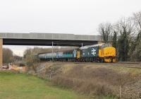 The <I>Bay Gateway</I> bridge over the WCML is an impressive structure but was only carrying construction traffic when 37402 propelled the Carlisle to Preston service under it on 1st April 2016. A short distance to the east another bridge carries the new road over the Lancaster Canal. What appears to be a single yellow signal is actually a flashing aspect indicating the next signal is also on yellow but the train is routed into the speed restricted Platform 4 line at Lancaster.<br><br>[Mark Bartlett 01/04/2016]