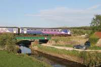 A pair of Class 153 single units cross a low bridge near Silverdale with a Barrow-in-Furness to Lancaster service on 12th May 2016. The watercourse in the foreground drains the nearby Leighton Moss RSPB reserve. <br><br>[Mark Bartlett 12/05/2016]