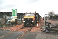A roadrail Unimog vehicle about to bring ballast wagons east over Cambus level crossing in December 2006 during reinstatement of the Stirling - Alloa line. Part of the huge Diageo site stands in the background..<br><br>[John Furnevel 15/12/2006]