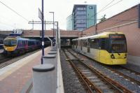 A Metrolink tram departs from Manchester Airport station heading to Cornbrook on 22 June 2016 while a TPE service to York waits on the left.<br><br>[John McIntyre 22/06/2016]
