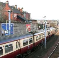 A Motherwell – Dalmuir train calls at Hamilton Central platform 1 on 17 March 2006. Note the building on the upper left with the covered stairway linked to the station's south wall. This is the former entrance and booking office on Kemp Street [see image 9044]. <br><br>[John Furnevel 17/03/2006]