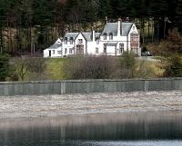 Magnificent Victoria Lodge, built by the men who financed the construction of the reservoir and the railway, stands on the hillside above the terminus. View looking east across Talla dam in 2004.<br><br>[John Furnevel 13/11/2004]