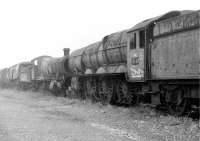 A very sad looking GWR 6023 <I>King Edward II</I>, in Barry scrapyard in 1975 with its rear driving wheels cut through. Beyond lie an equally decrepit GWR 2-8-0 and a Bulleid Light Pacific. At the time the painted <I>Reserved</I> notices on the King seemed optimistic but the Great Western Society has done a magnificent job of restoration [See image 58065].<br><br>[Mark Bartlett 28/10/1975]