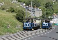 <I>Halfway to Halfway</I>. Trams 4 & 5 pass at the lower section loop of the Great Orme Tramway on 26th July 2017. Above this point the tracks are interlaced but below here there is just a single track dropping down a 1:4 gradient to Victoria station. Cars on the lower (street running) section have protective valances rather than an open chassis. The descending car moves the trailing point blade so that it takes the correct line coming back up again and wires don't get crossed!<br><br>[Mark Bartlett 26/07/2017]