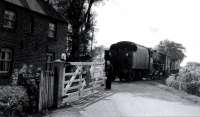 An unidentified LMS Black 5 crossing the minor road at Cogie Hill with a goods train returning from Pilling towards Garstang, probably sometime in the early 1960s. Between 1908 and the 1930 withdrawal of passenger services there was a small request halt here. The crossing keeper's cottage survived the 1963 closure of the line. [See image 18313] for a modern day comparison from the same spot.<br><br>[Knott End Collection //]