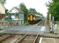 A DMU for Great Yarmouth leaves Cantley, Norfolk, on 19 July 2002. Platform view east over Station Road level crossing.  <br><br>[Ian Dinmore 19/07/2002]