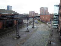 After fourteen years as a passenger station Liverpool Road was replaced by Manchester Victoria but continued in use as a Goods Depot until 1975. Many of the freight facilities can still be seen in its new role as part of the Museum of Science and Industry. This view taken from the main museum building in October 2017 shows the old sidings, the passenger station where the lines converge and the <I>Power Hall</I> on the left where the railway exhibits are housed. <br><br>[Mark Bartlett 08/10/2017]