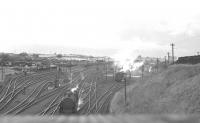 The south end of the shed yard at Kingmoor in the spring of 1962. View is north over the turntable towards the running shed, shrouded in smoke and steam as usual, with the coaling plant visible on the right beyond the end of the sleeper fence.<br><br>[K A Gray //1962]