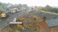 Lots of activity surrounding the arrival of an engineering train at Haltwhistle in October 1989. A Class 37 propels its wagons into a siding in the engineer's yard in the autumn mist. A tamper had already moved into another siding behind the platform.<br><br>[Charlie Niven /10/1989]
