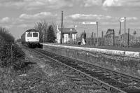 The country halt atmosphere at Bures on the Suffolk/Essex border is completed by the obligatory lady with a shopping bag. She has just alighted from the Cravens DMU on the departing service to Sudbury on 22nd March 1980, having probably spent the Saturday morning exploring the stores in Colchester. In 2017, the station became a 'request stop'.<br><br>[Mark Dufton 22/03/1980]