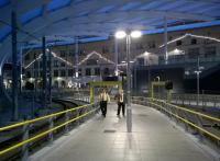 The ends of the old roof panels at Manchester Victoria have been replaced with strings of lights, which has the odd effect of making the station look a bit like a theatre at night. As the approaching Metrolink staff might respond with Northern humour, 'it's always a song and dance round here'.<br><br>[Ken Strachan 18/07/2015]