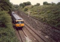 Dropping from Knightswood North Junction to Knightswood South Junction is a 303 about to pass under the Westerton-Cowlairs  line (right).<br><br>[Ewan Crawford //1987]