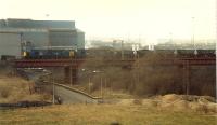 A Hunterston-Ravenscraig coal train crosses the Calder Viaduct and reaches the end of its journey and is about to enter Ravenscraig No 2 yard. The building behind the locomotives is the Sinter Plant.<br><br>[Ewan Crawford //1988]