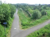 Remains of Westcraigs station looking east towards Armadale in June 2006. The 1862 station, built by the Bathgate & Coatbridge Railway, was located on the southern edge of the village of Blackridge in West Lothian and one and a half miles north of Harthill. Westcraigs lost its passenger service in 1956. [The station appeared in some timetables as <I>Westcraigs for Harthill</I>.] Platform remains can be seen together with part of the goods facilities to the right. Above these in the background is the roof of the station house, now in private ownership. Plans are afoot to build a new station to the east of here as part of the Airdrie - Bathgate reopening, although it would be named Blackridge, rather than Westcraigs. <br><br>[John Furnevel 12/06/2006]